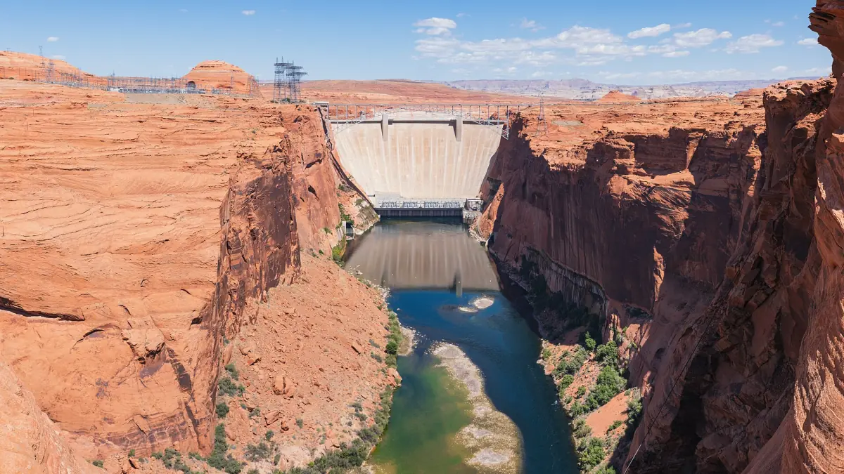 Glen Canyon Dam von flussabwärts gesehen zwischen roten Felswänden über dem Fluss