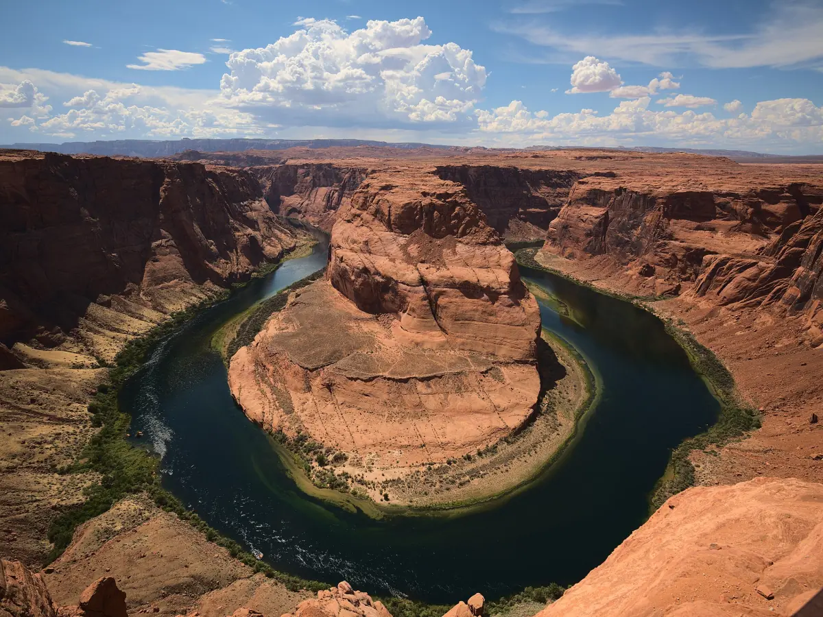 Weiter Blick auf den Horseshoe Bend mit grünem Fluss und Canyonwänden unter Wolken