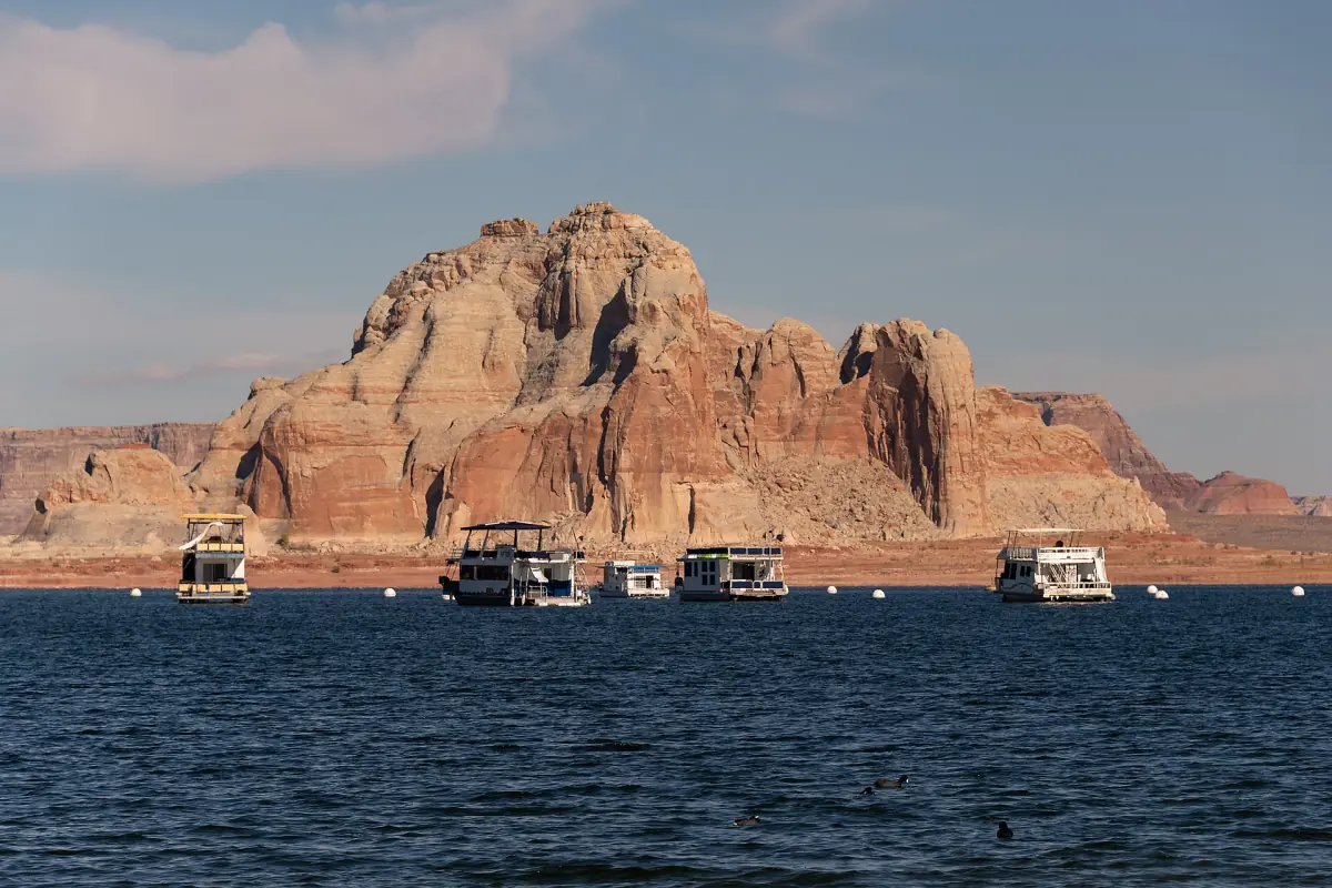 Hausboote liegen unterhalb eines roten Sandsteinfelsens auf dem Lake Powell vor Anker
