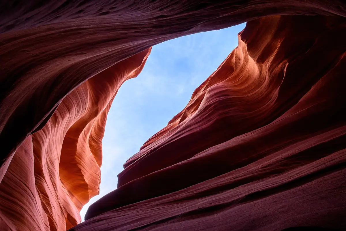 Geschwungene rote Sandsteinwände des Lower Antelope Canyon rahmen einen schmalen Streifen blauen Himmel