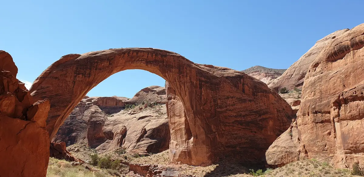 Die Rainbow Bridge, ein riesiger roter Sandsteinbogen, unter klarem blauem Himmel