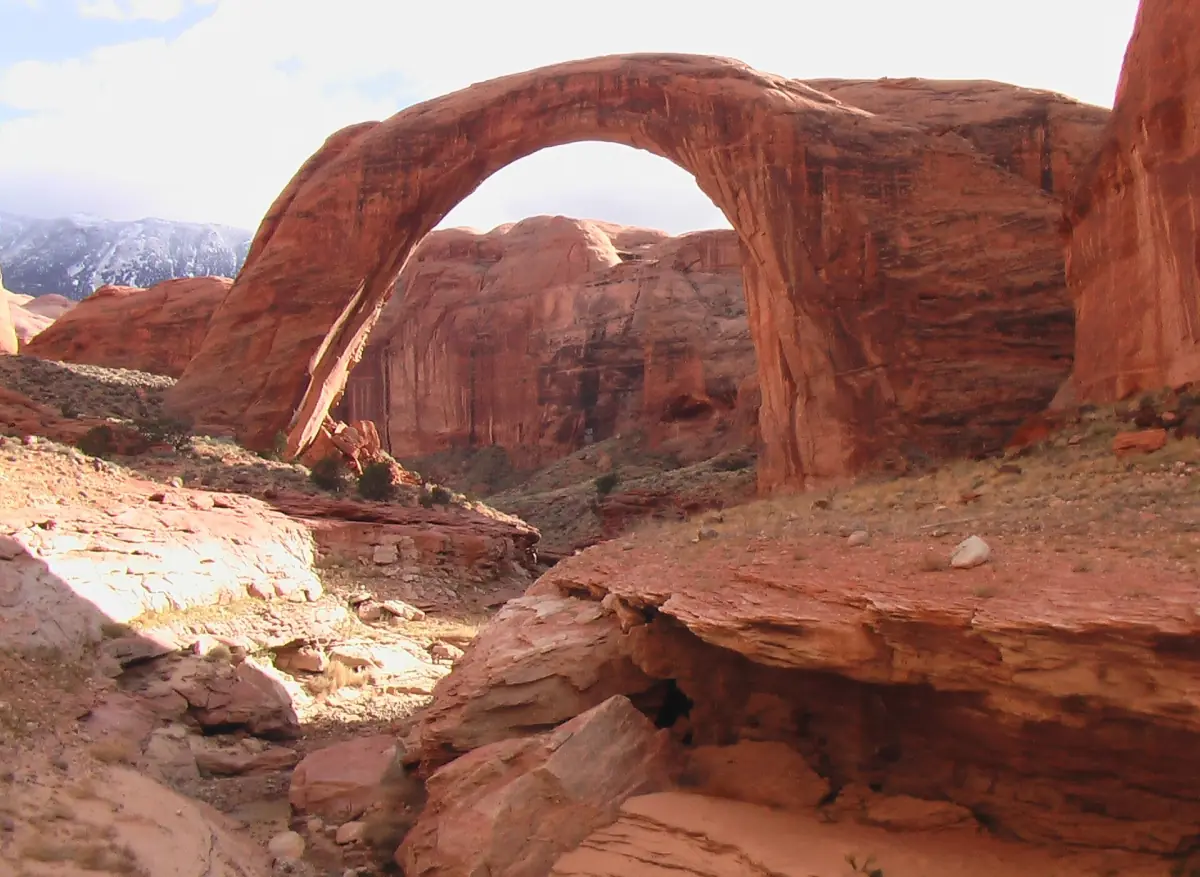 Roter Sandsteinbogen der Rainbow Bridge, gesehen über glatten Felsen